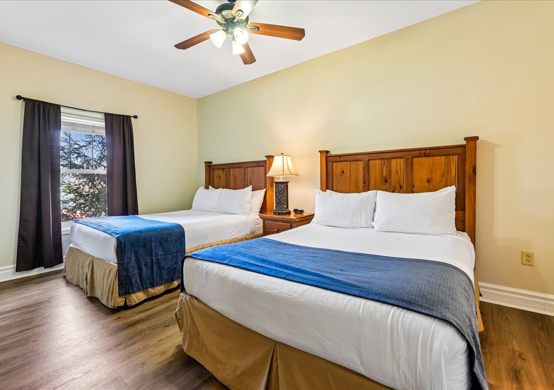 Unwind in your cozy twin bedroom with rustic wood headboards, crisp linens, and a gentle ceiling fan keeping you comfortable all night long.