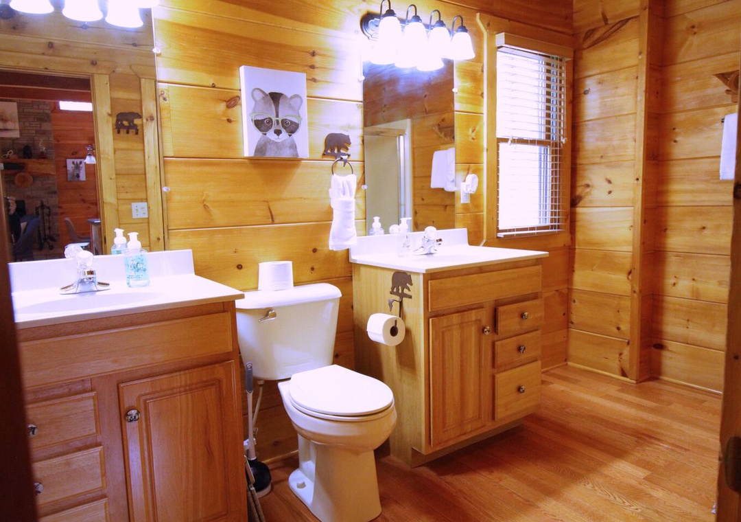 Rustic charm meets modern comfort in your private bathroom with dual vanities, warm wood walls, and thoughtful amenities for your stay.