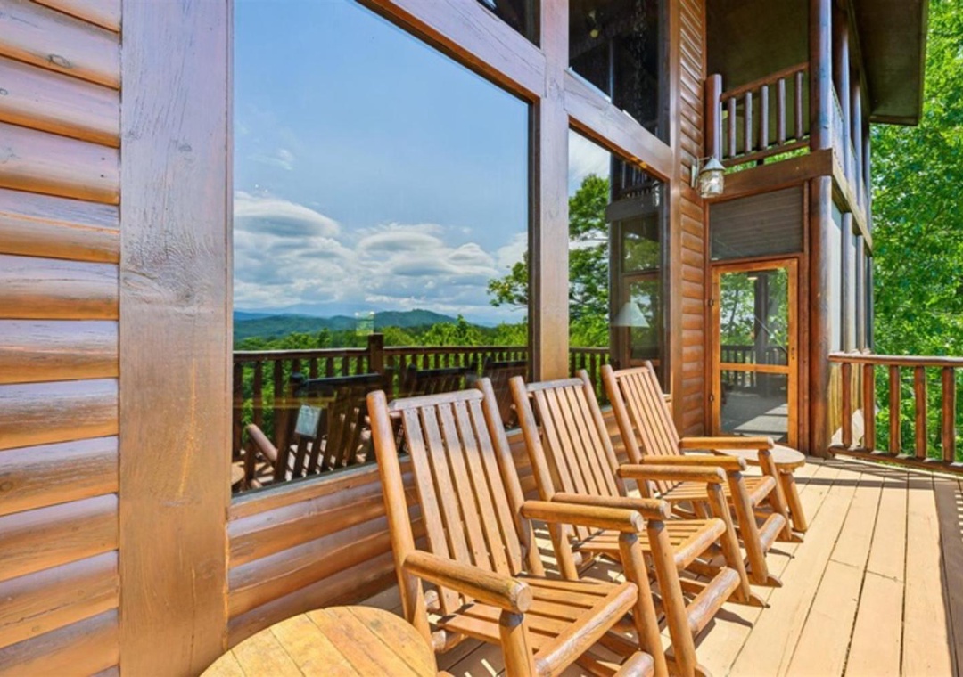 Scenic mountain-view deck with log-cabin exterior and multi-level covered porches nestled in a lush, forested setting.