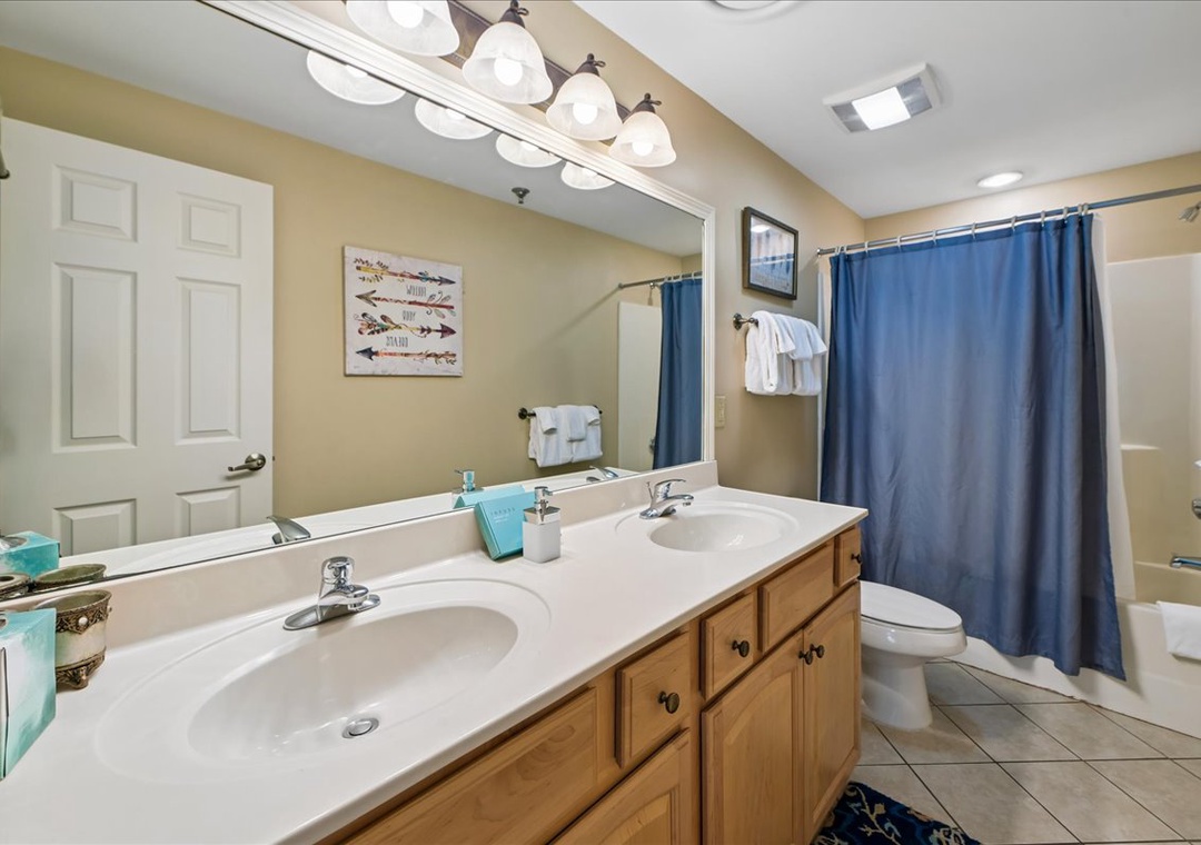 Freshen up in your spacious bathroom featuring dual sinks, bright vanity lighting, and a relaxing shower area.