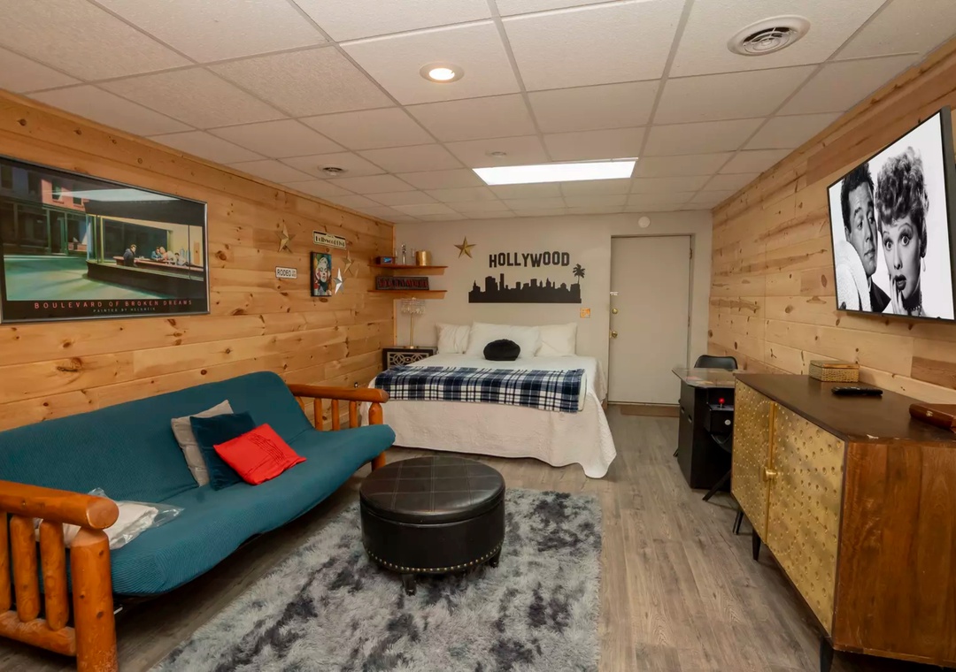 Your cozy studio combines rustic wood warmth with modern comfort, featuring a plush futon, entertainment setup, and charming Hollywood-themed decor.