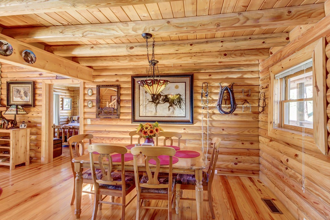 Step into the warmth of this handcrafted log cabin dining space, where natural wood surrounds you and rustic charm invites lingering meals. Gather around the table under a beautifully crafted chandelier for memorable moments together.