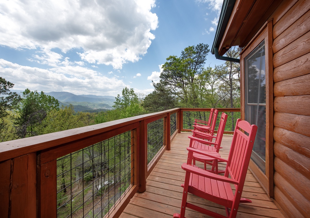 Settle into vibrant red rockers on your private mountain deck, where endless views stretch across rolling hills and forests.