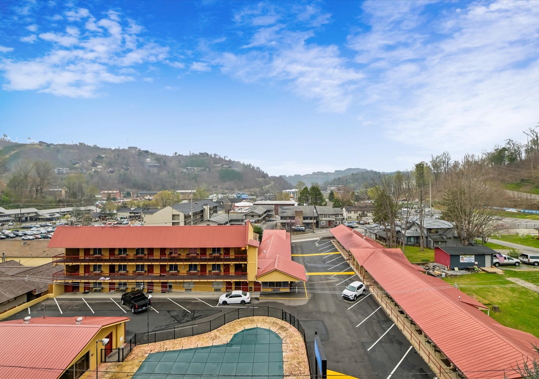 Aerial view of the property nestled in scenic mountain foothills, with convenient parking and easy access to the surrounding area.