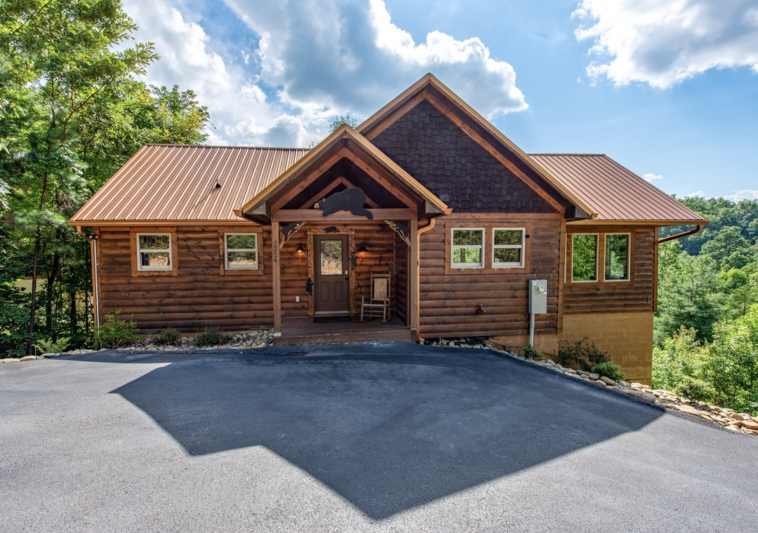 A beautiful log cabin retreat nestled among lush mountain greenery with ample parking for your arrival. The property's warm, natural wood exterior and forest surroundings set the tone for a tranquil getaway.