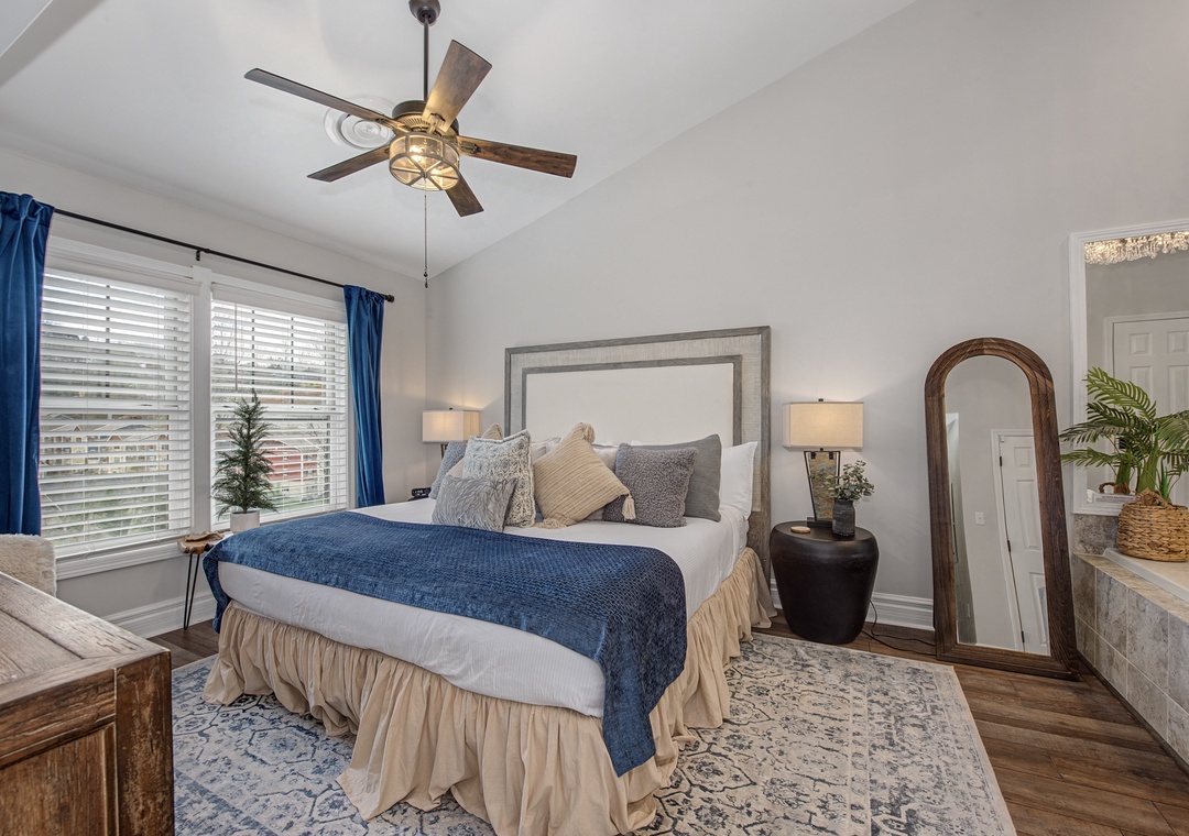 Sink into plush bedding beneath your rustic ceiling fan, where blue accents and warm lighting create the perfect retreat for restful nights.