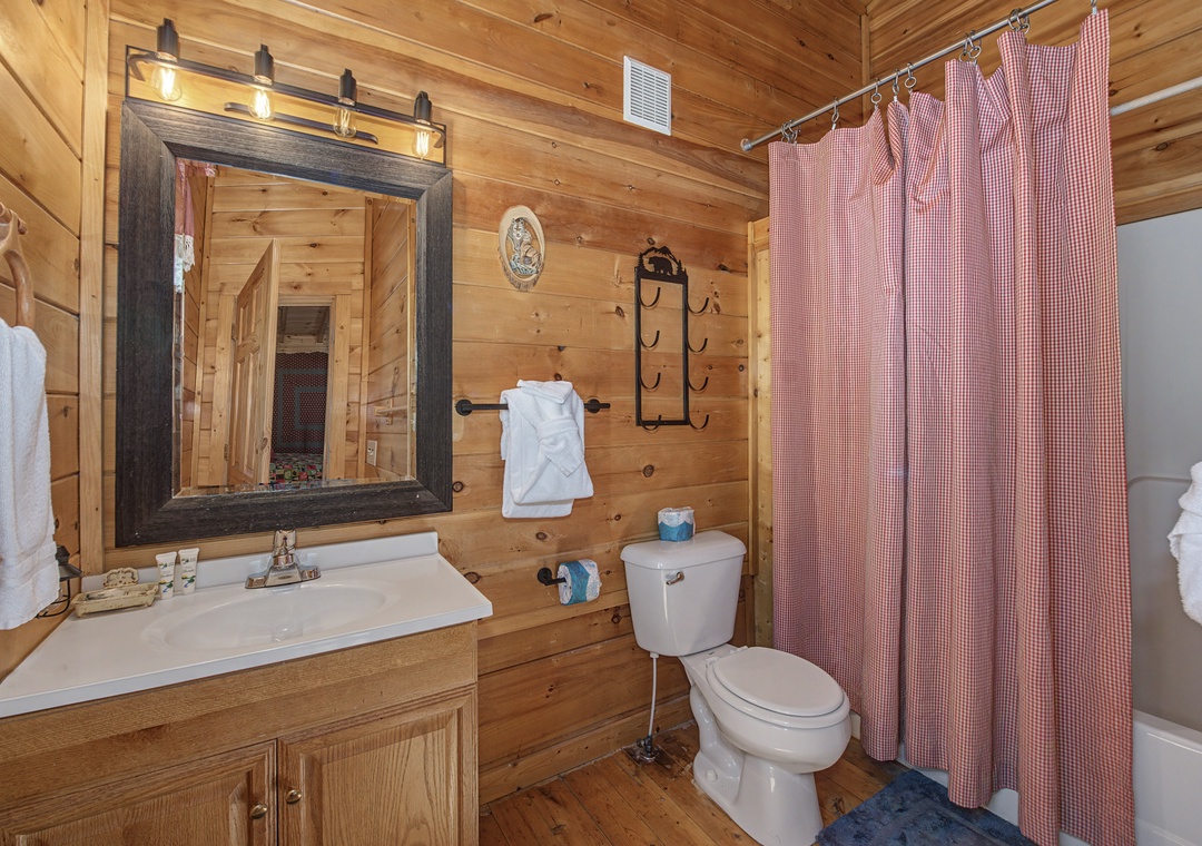 Unwind in your rustic bathroom featuring warm wood walls and modern amenities for a cozy retreat.