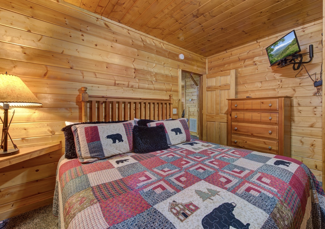 Your cozy log cabin bedroom wraps you in rustic charm with warm wood walls, charming bear-themed quilts, and modern touches for comfort.