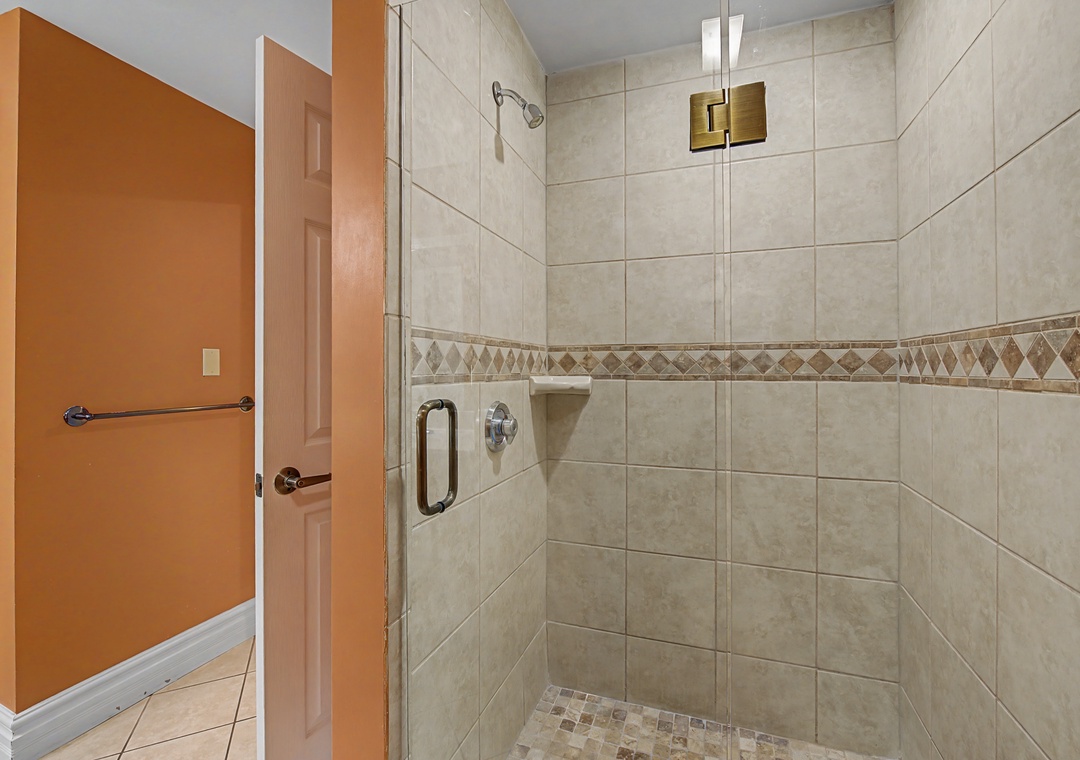 Step into your spacious glass-enclosed shower featuring elegant tile work and modern fixtures for a refreshing start to your day.