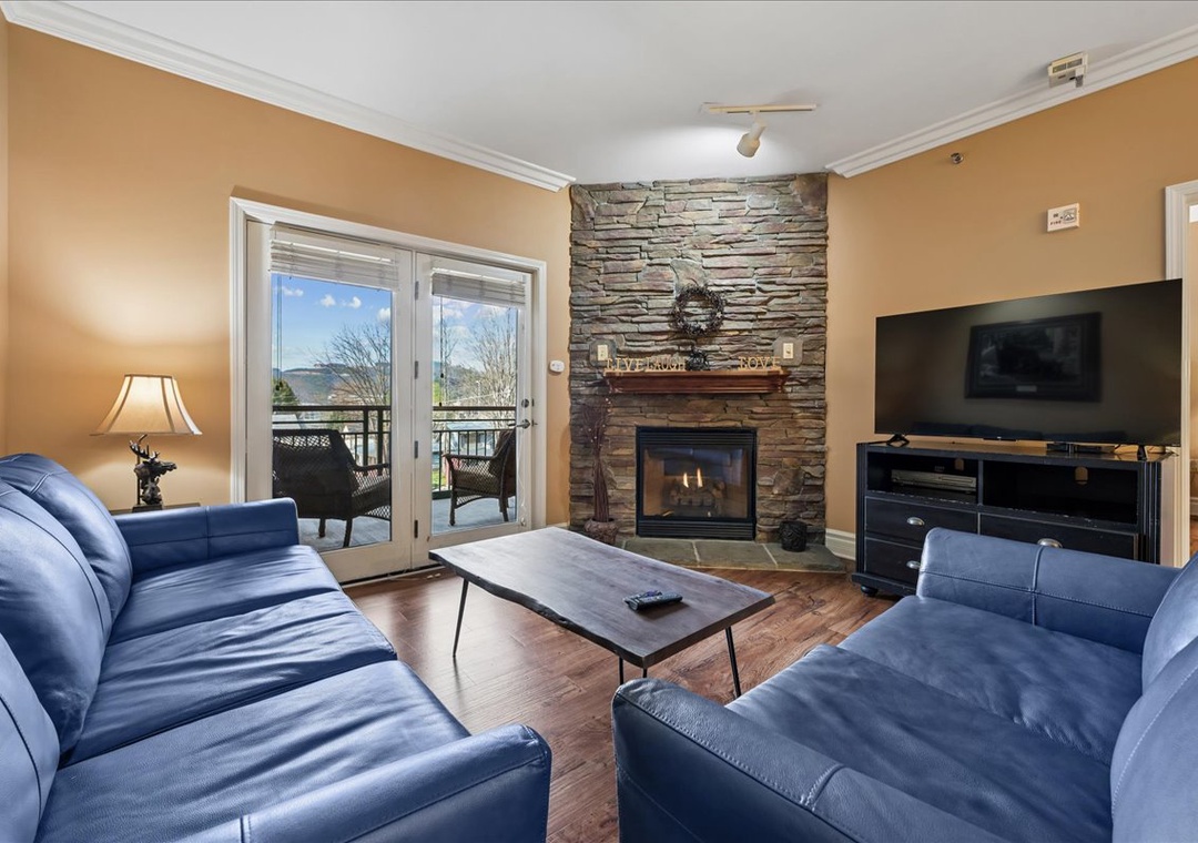 Relax in your cozy living room with stone fireplace, plush leather seating, and flat-screen TV—perfect for unwinding after mountain adventures.
