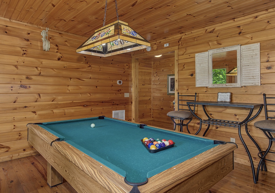 Your private game room awaits with a full-size billiards table, cozy dining nook by the window, and warm wood paneling creating the perfect retreat for friendly competition and relaxation.
