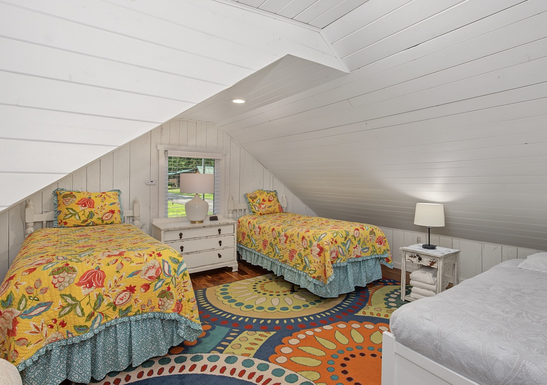 Cozy attic bedroom with cheerful floral bedding and a vibrant, patterned rug that brings personality to your retreat under the eaves.