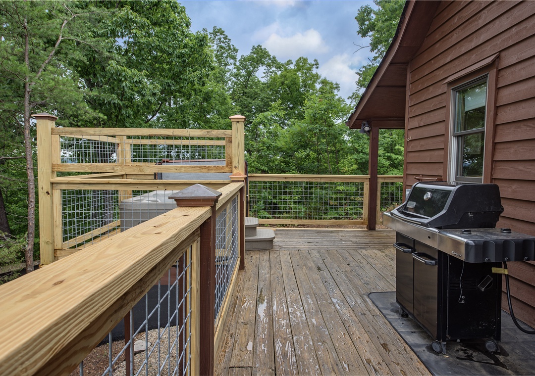 A spacious wooden deck with forest views invites your outdoor dining and grilling adventures, complete with a hot tub for unwinding after exploring nearby trails.