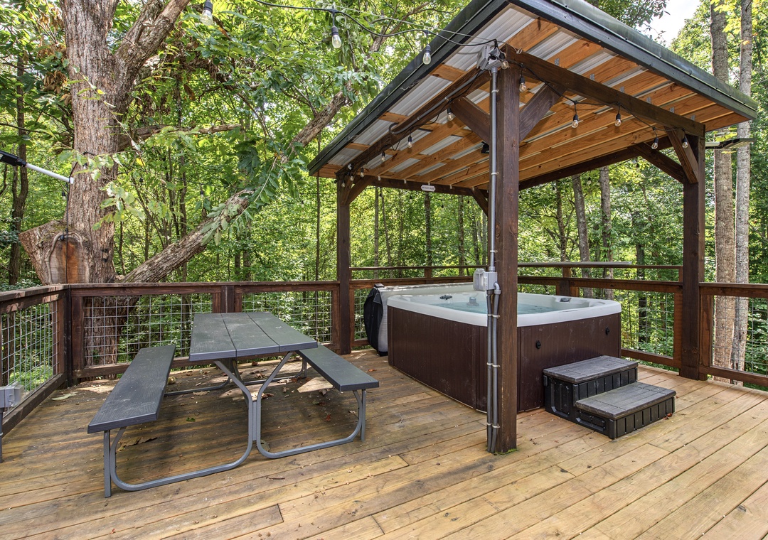 Soak under the stars in your private hot tub, sheltered by a charming pavilion and surrounded by lush forest. The picnic table invites leisurely outdoor meals in this peaceful woodland retreat.