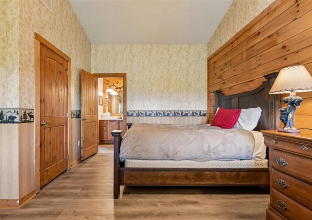 Your spacious bedroom blends rustic charm with comfortable elegance, featuring a handsome wood-paneled accent wall, quality linens, and warm lighting for truly restful nights.