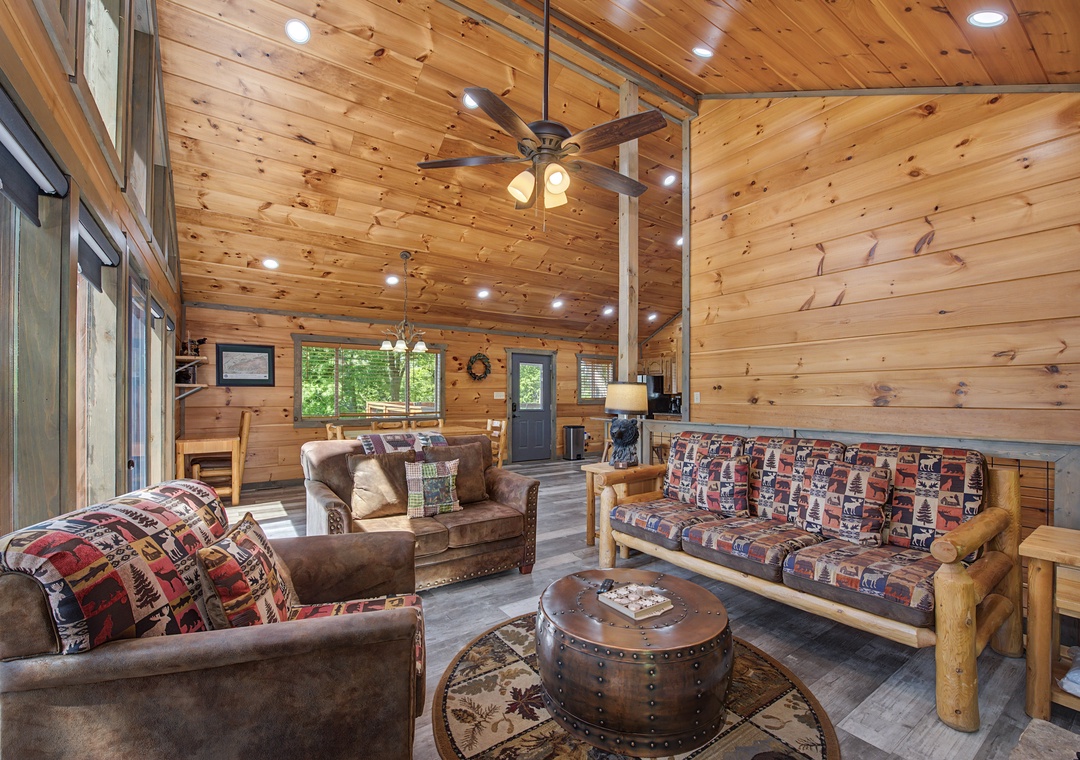 Unwind in your warm, airy cabin living room with soaring wood-paneled ceilings, plush seating, and rustic charm inviting you to relax and feel at home.