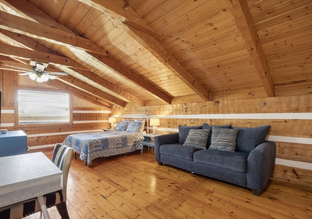 Your cozy loft bedroom blends rustic charm with modern comfort, featuring warm wood beams and a plush sofa for relaxing.