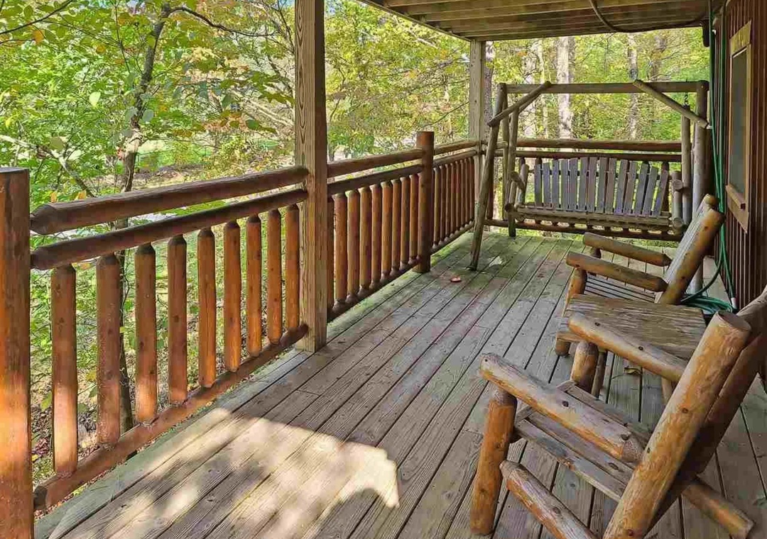 Unwind on your private covered deck with rustic log furniture and peaceful forest views—your perfect retreat for morning coffee.