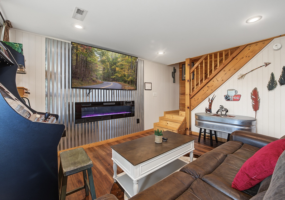 Unwind in your cozy living space featuring a modern fireplace, comfortable seating, and rustic cabin charm. The open layout connects you to a fully equipped kitchen, perfect for relaxing evenings together.