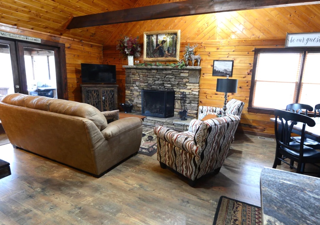 Unwind by your stone fireplace in this cozy cabin living room with rustic charm and comfortable seating.