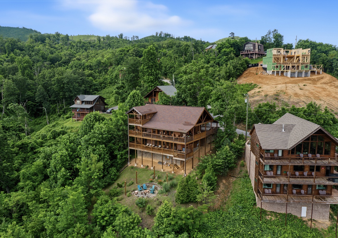 Aerial view of mountain retreat cabins nestled into lush forested hillsides, showcasing the property's natural setting and development.