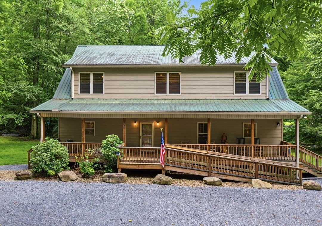 A spacious two-story retreat nestled in lush greenery, featuring a welcoming front porch and convenient parking for a peaceful woodland getaway.