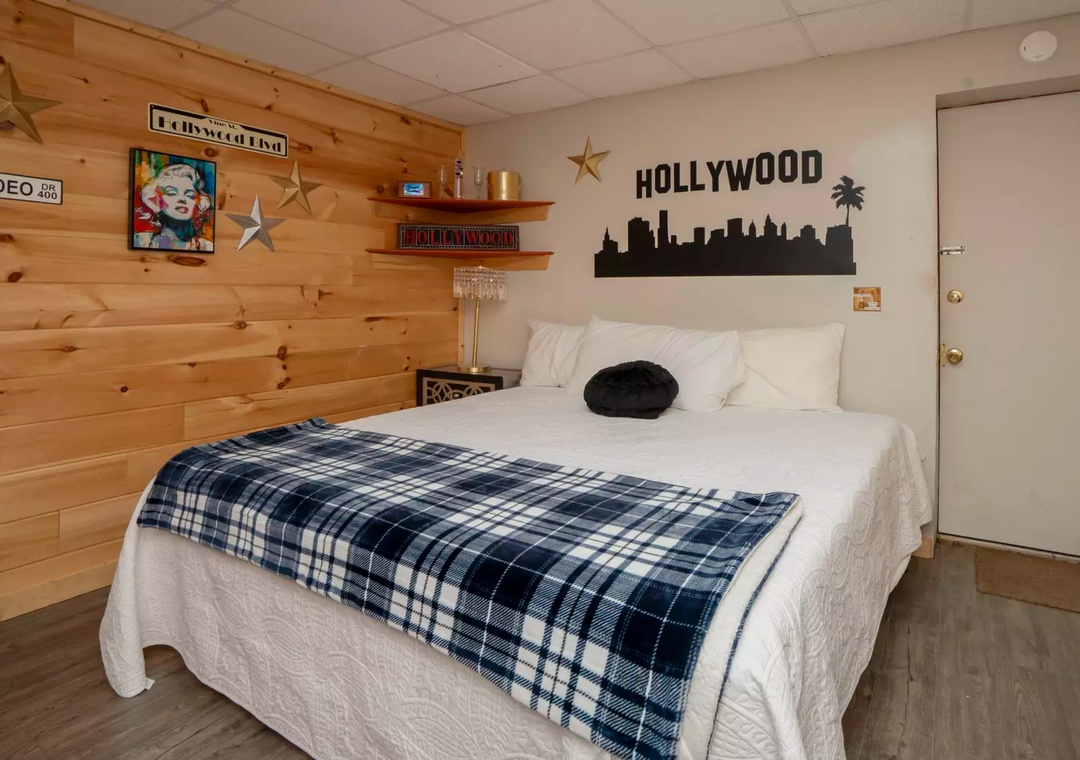 Your Hollywood-themed bedroom combines rustic wood walls with city glamour, featuring a comfortable bed and unique decor for memorable nights.