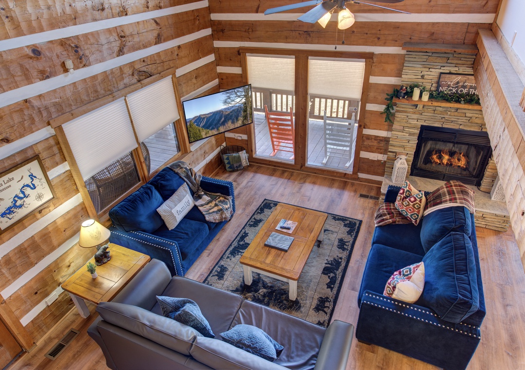 Unwind in this cozy cabin living room where rustic charm meets comfort—plush sofas surround a crackling fireplace while mountain views beckon through your private balcony doors.