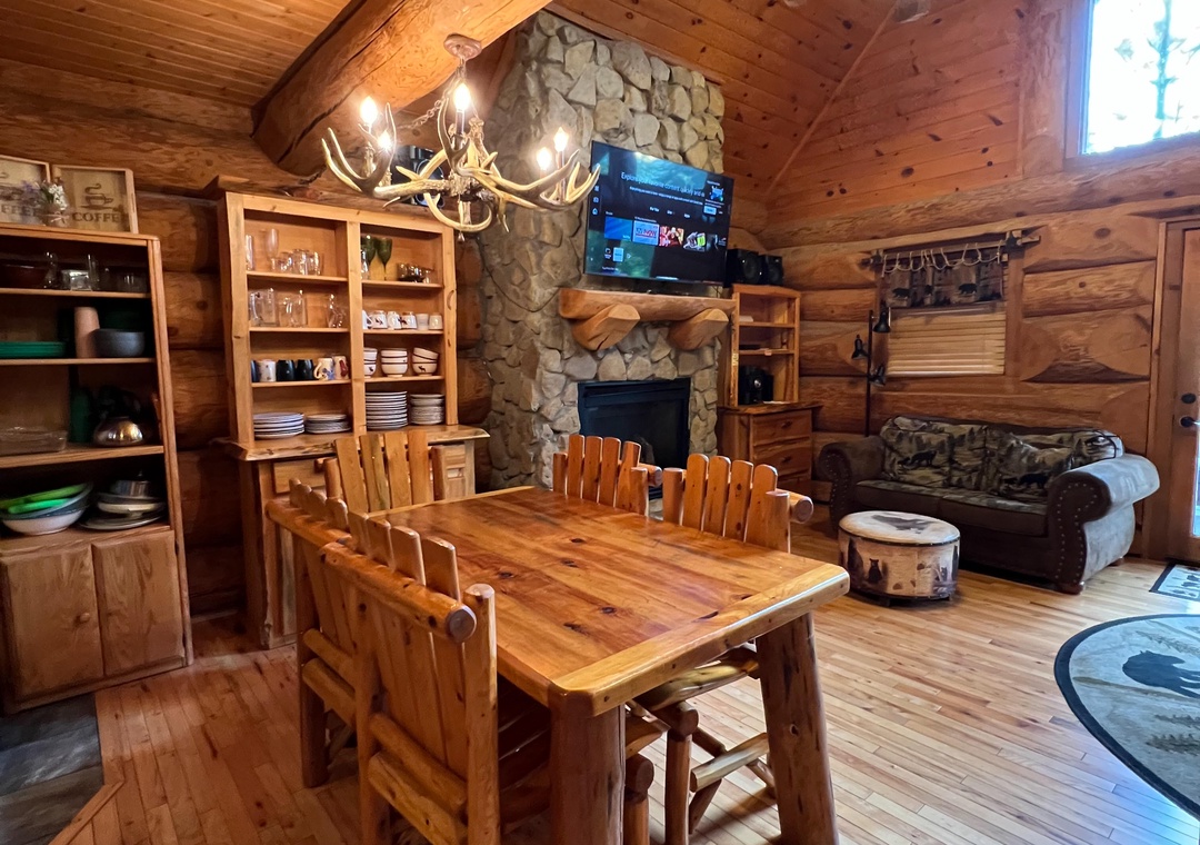 Gather around the handcrafted wood table under vaulted ceilings and warm lighting, where the stone fireplace creates a cozy focal point for your group meals and evening conversations.