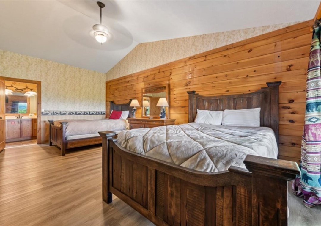 Slip into your cozy cabin retreat with warm wood-paneled walls and two inviting beds dressed in soft linens, perfect for restful nights after exploring.