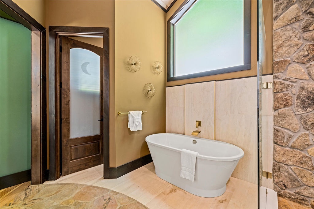 Soak in this luxurious freestanding tub while natural light streams through the skylight above. The spa-like atmosphere, elegant stone accents, and thoughtful design create your perfect retreat after a day of exploring.