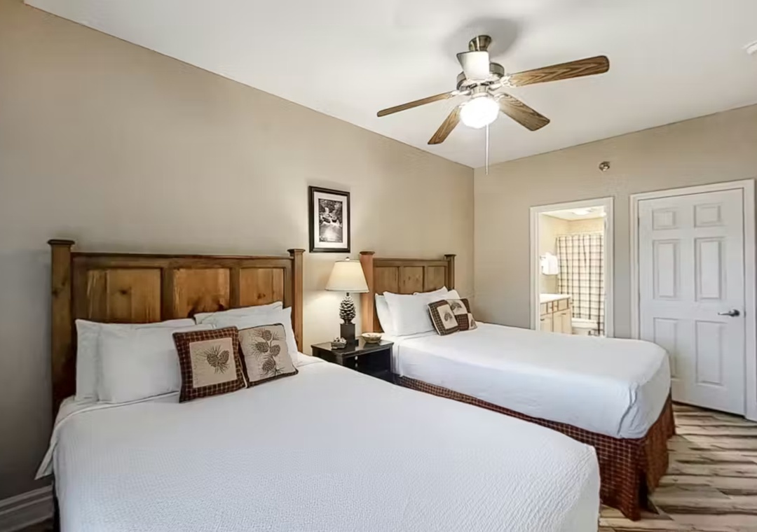 Rest peacefully in your cozy twin bedroom with rustic wood headboards, crisp linens, and a gentle ceiling fan overhead.