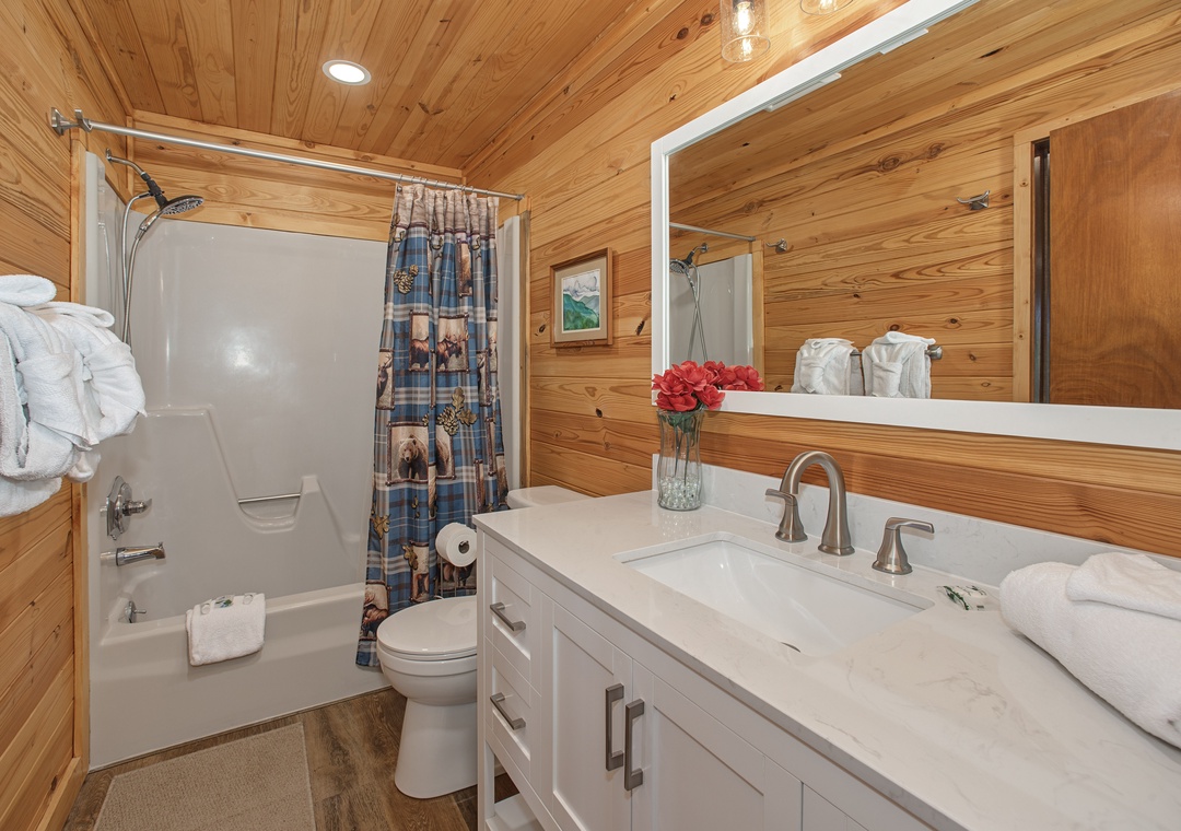 Step into your rustic yet refined bathroom, where warm wood paneling creates a cozy cabin feel. Fresh towels await you on the marble-topped vanity, while the tub/shower combo invites you to unwind after a day of adventure.