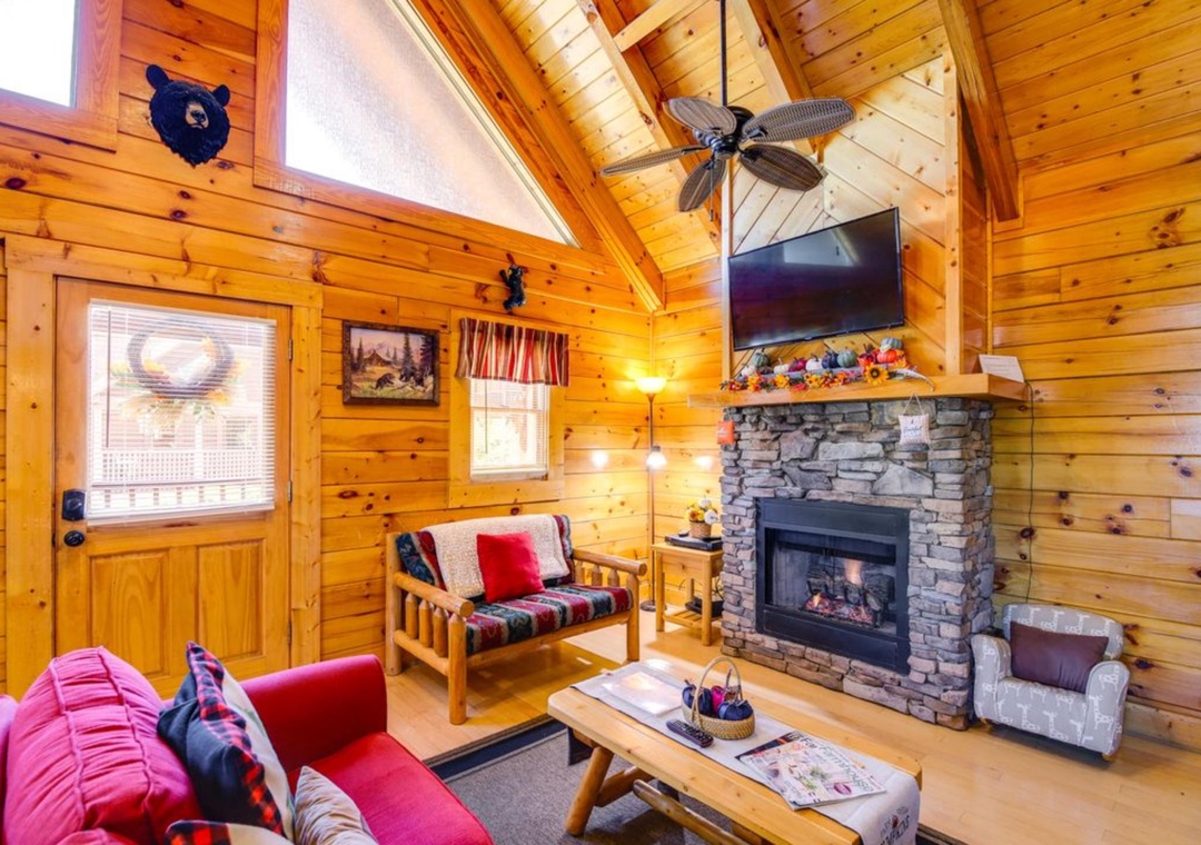 Cozy up by your crackling stone fireplace in this rustic cabin living room with warm wood walls and comfortable seating.