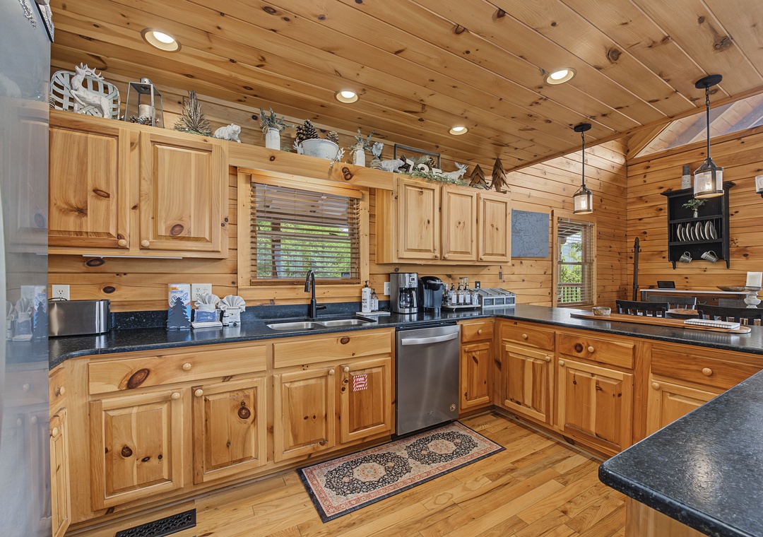 Imagine preparing your morning coffee in this spacious cabin kitchen, where warm wood tones and granite counters invite you to gather and cook together, surrounded by mountain charm.