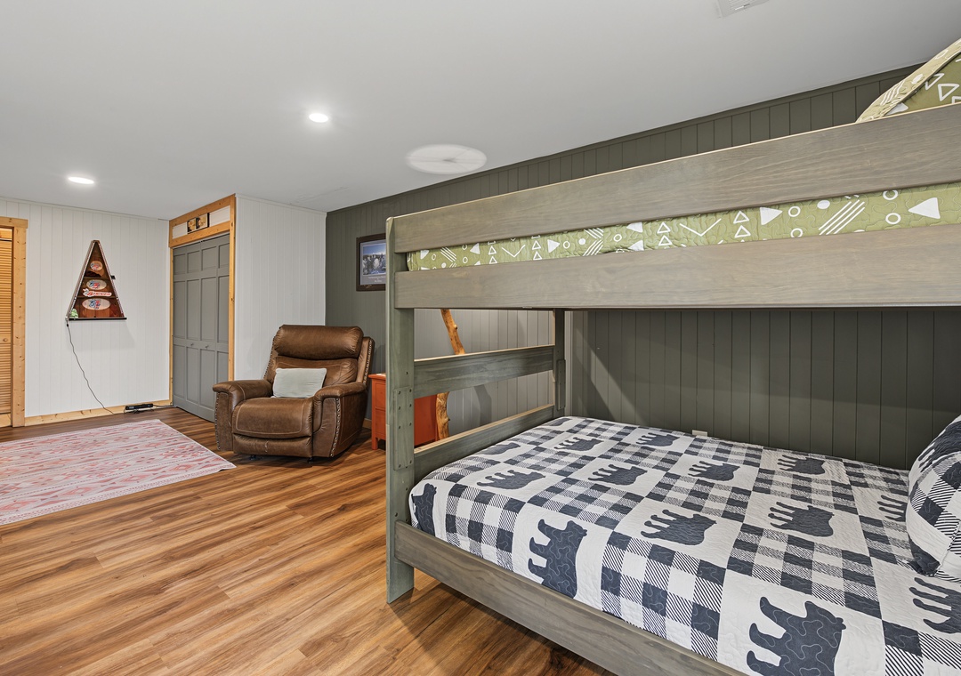 Spacious bedroom with charming bunk beds and a cozy armchair where you can unwind after your mountain adventures, featuring warm wood floors and rustic cabin details.