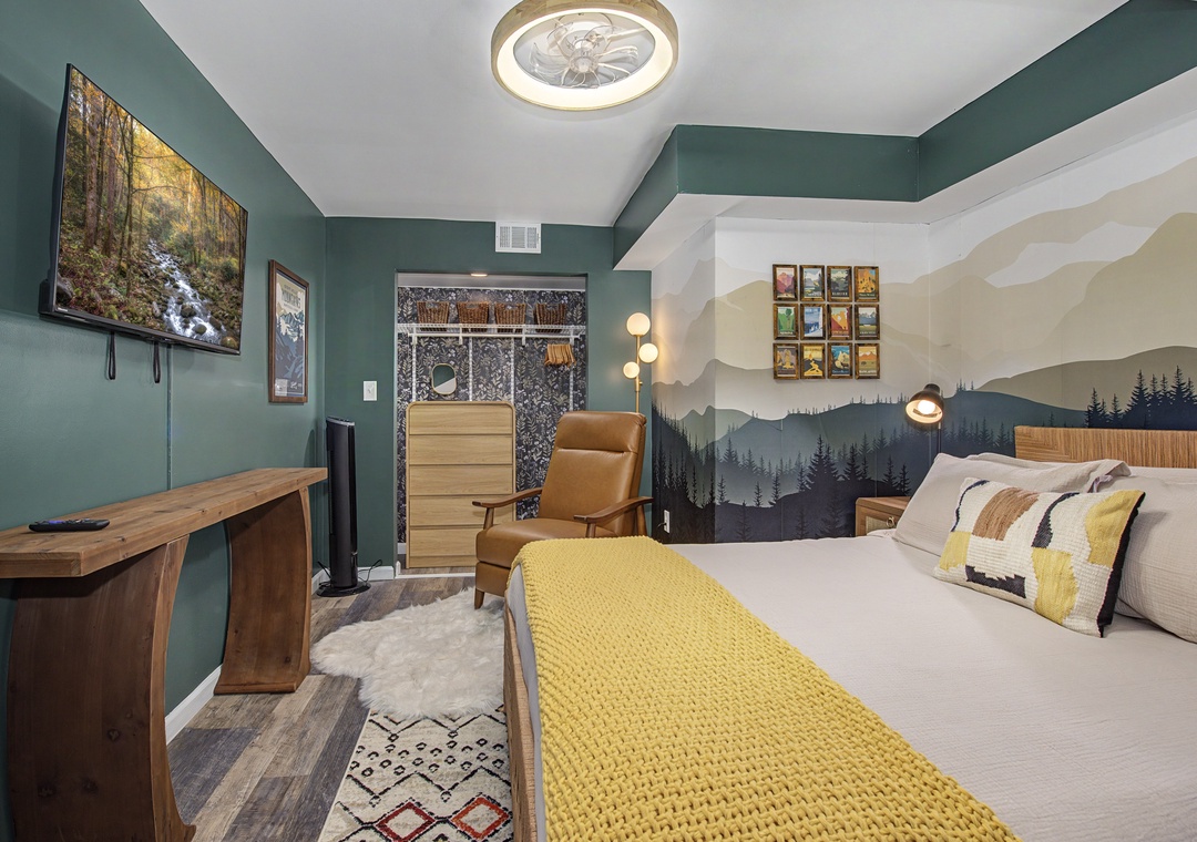 Unwind in your serene bedroom featuring a plush king bed, mountain mural, and cozy reading chair—your perfect retreat after a day exploring.