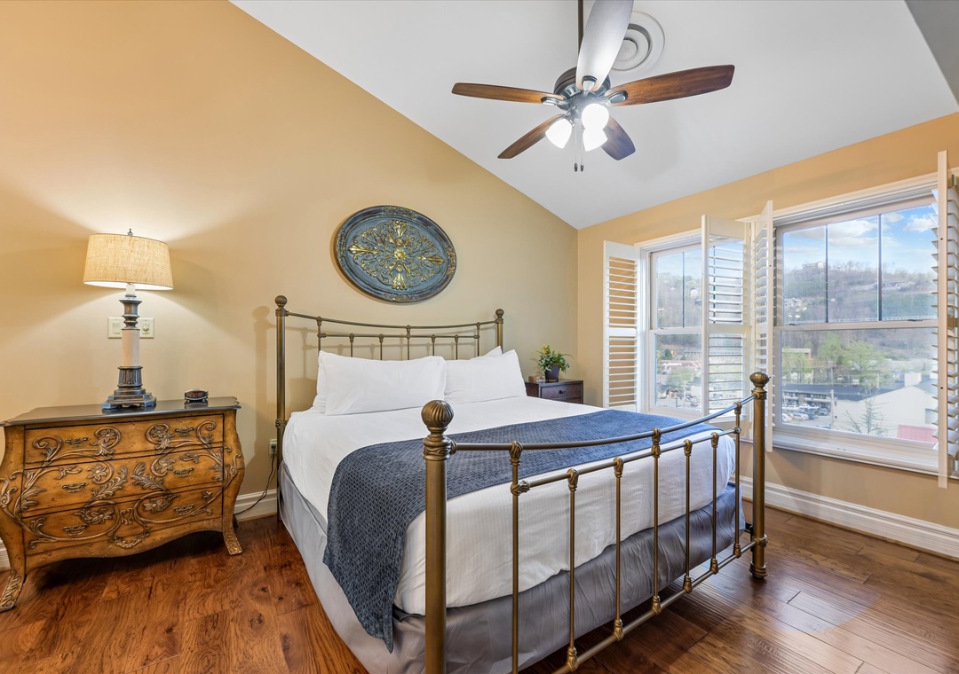 Wake up refreshed in your elegant bedroom featuring a vintage brass bed, hardwood floors, and bright windows with city views.