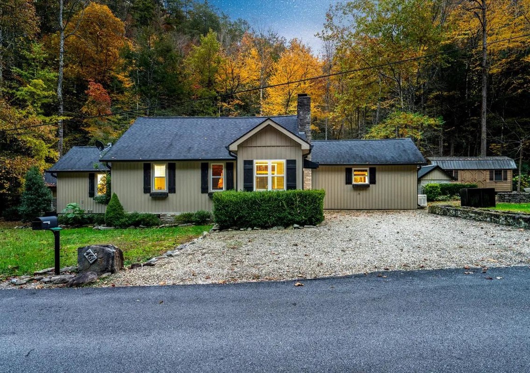 A welcoming property nestled among vibrant autumn foliage, featuring convenient gravel parking and a peaceful mountain neighborhood setting.
