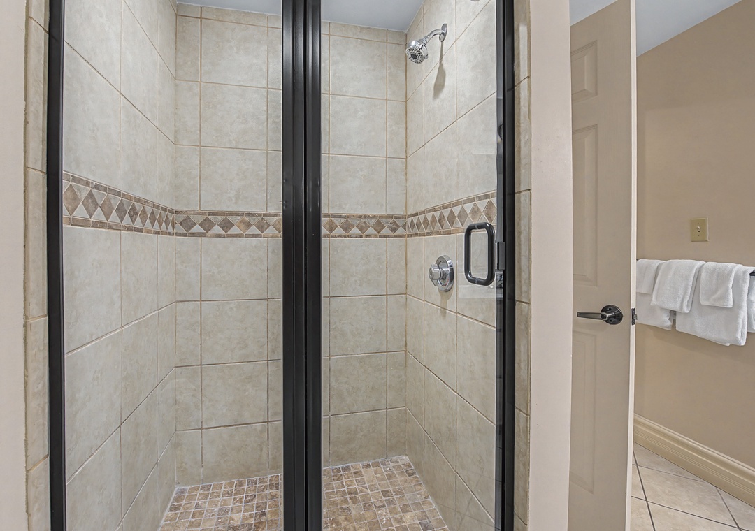Step into your elegant tiled shower with decorative accents and glass doors—perfect for refreshing after your adventures.