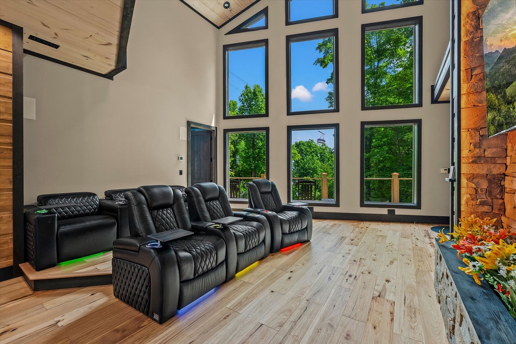Sink into plush theater seating while soaring windows frame lush forest views—your private escape for movie nights with nature as the backdrop.