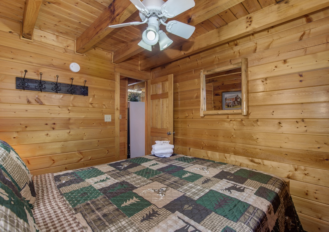 Relax in your cozy log cabin bedroom with rustic wood walls, wilderness-themed quilts, and authentic touches that create the perfect mountain retreat atmosphere.