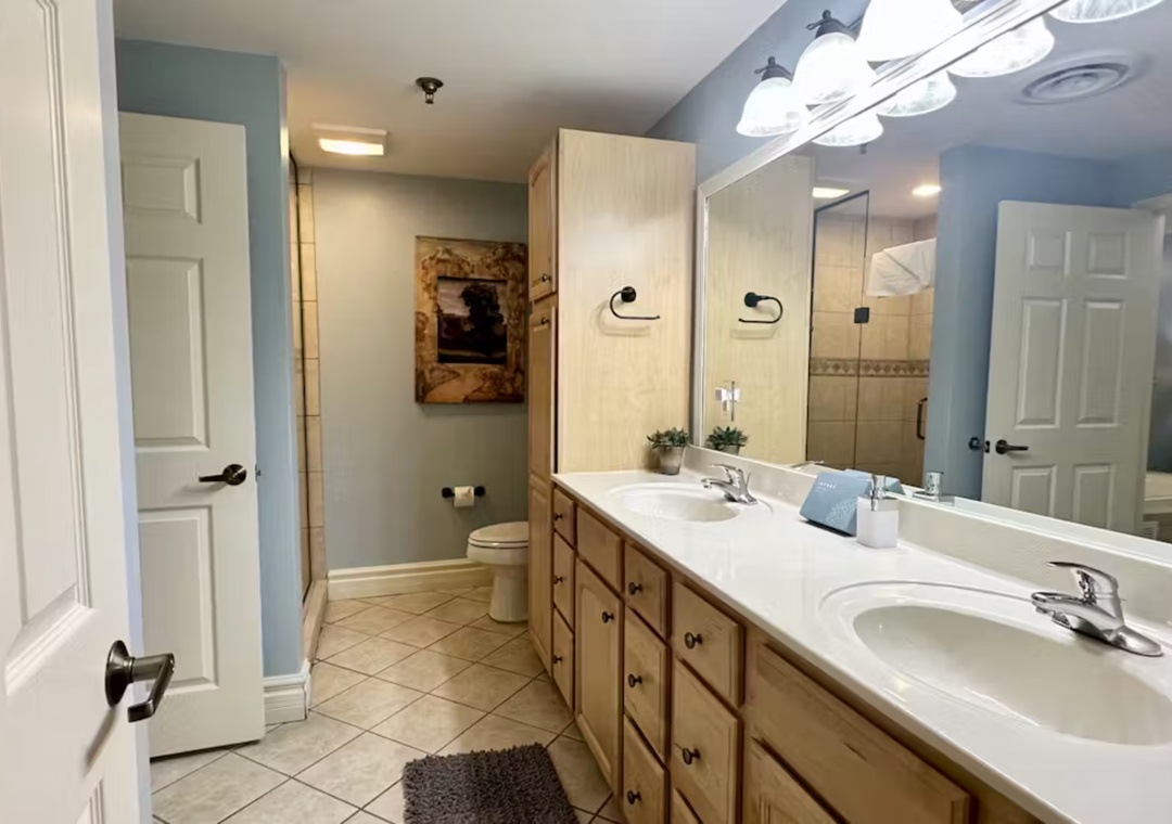 Freshen up in your spacious master bathroom with dual vanities, ample storage, and calming blue walls that create a peaceful retreat.