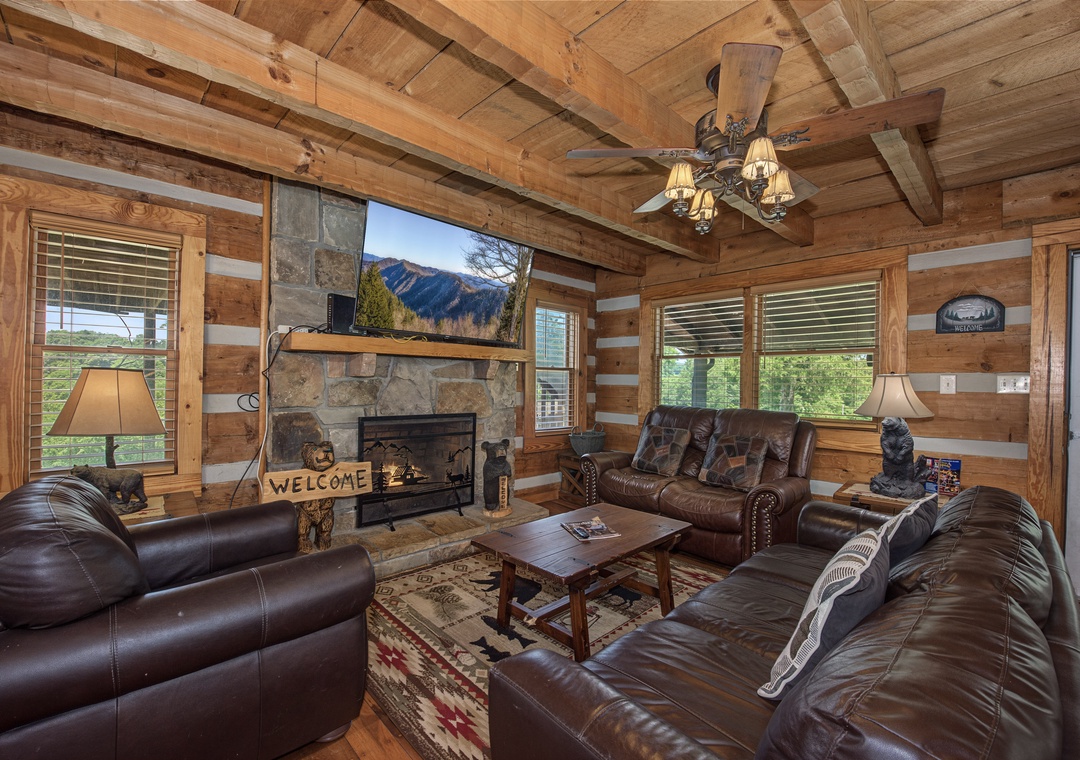 Sink into plush leather sofas beneath rustic beams as the stone fireplace warms your mountain getaway. Natural light fills your cozy retreat, perfect for unwinding after a day exploring.