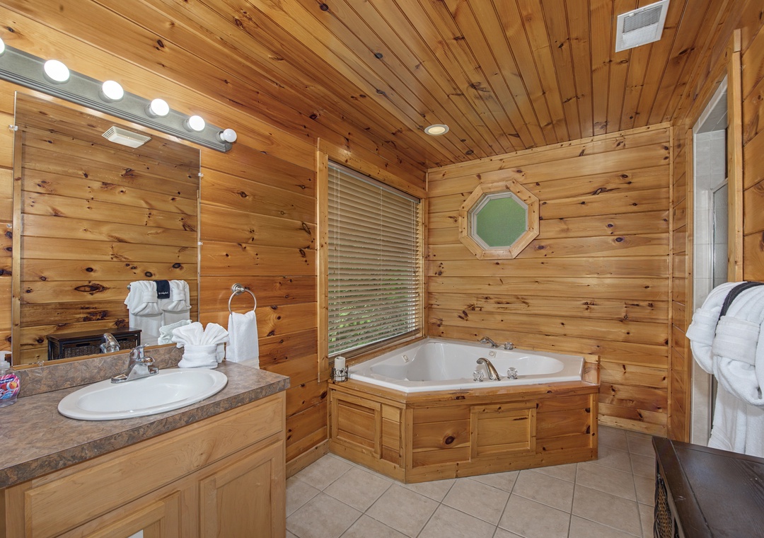Unwind in your private bathroom with warm wood walls, a soaking tub, and vanity lighting that sets the perfect mood for relaxation.