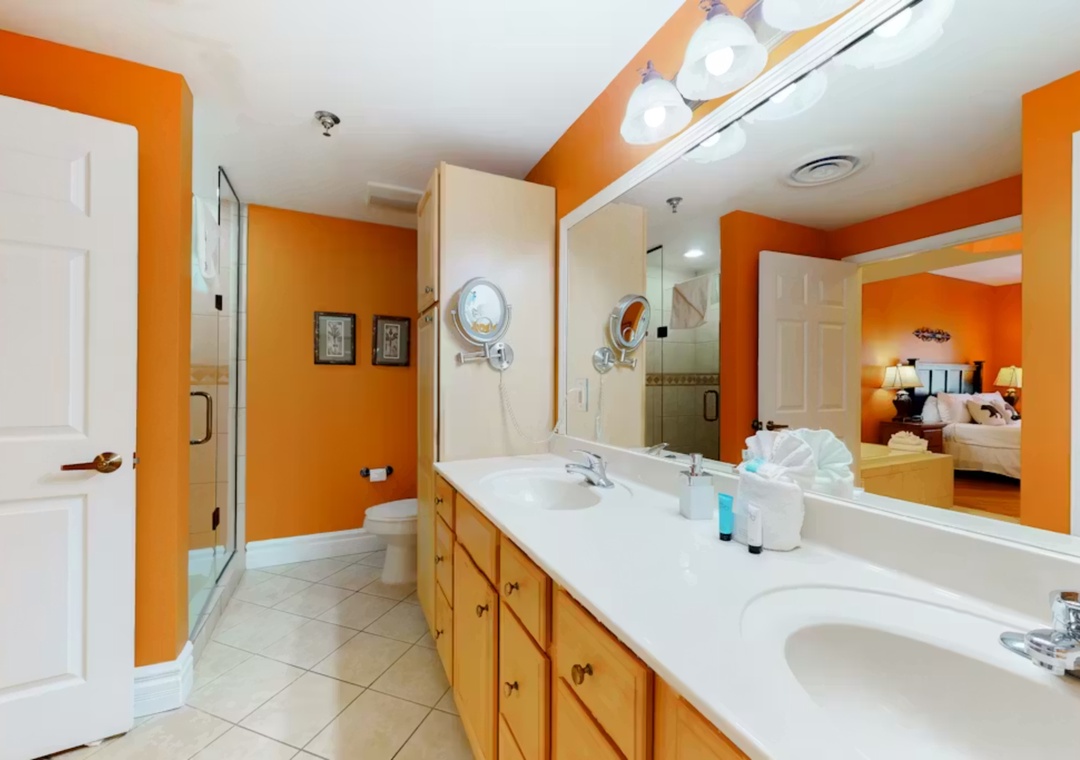 Step into your vibrant ensuite bathroom with dual sinks and bright orange walls that energize your morning routine.