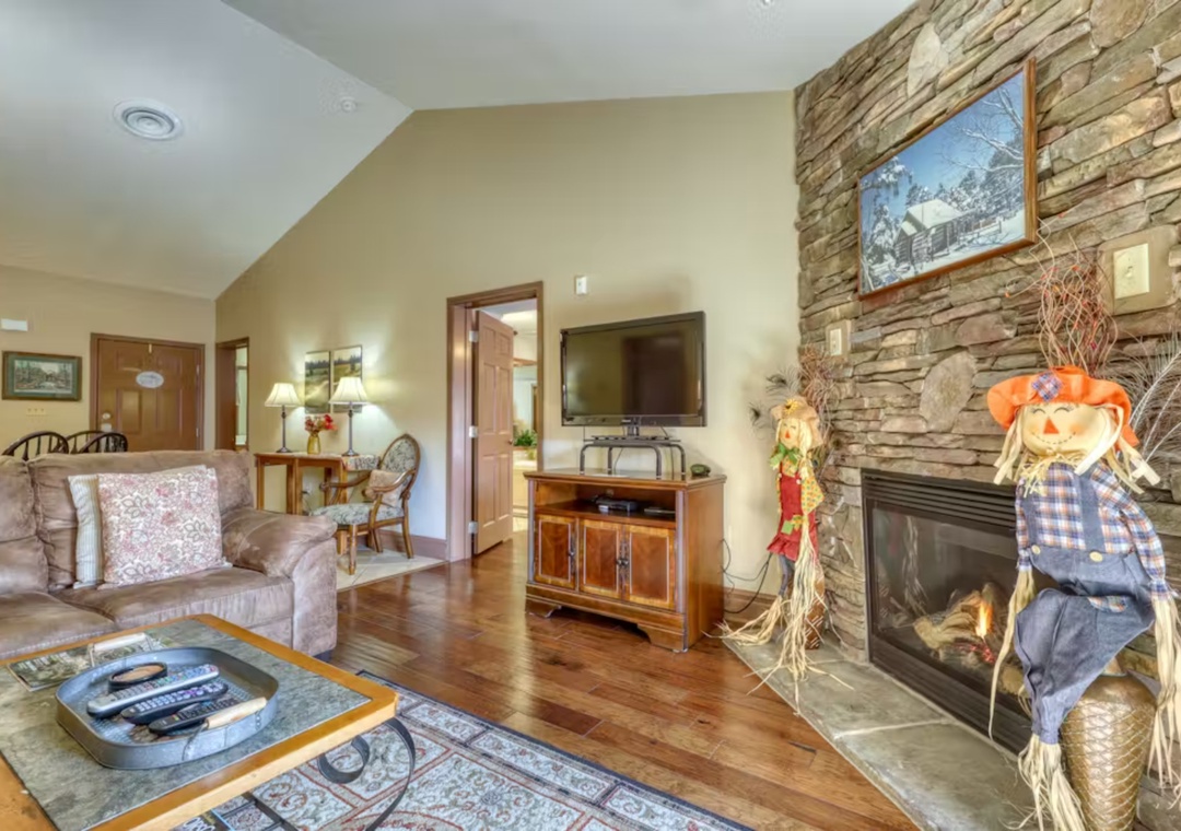 Cozy up in your spacious living room with crackling fireplace, comfortable seating, and rustic stone accent wall.