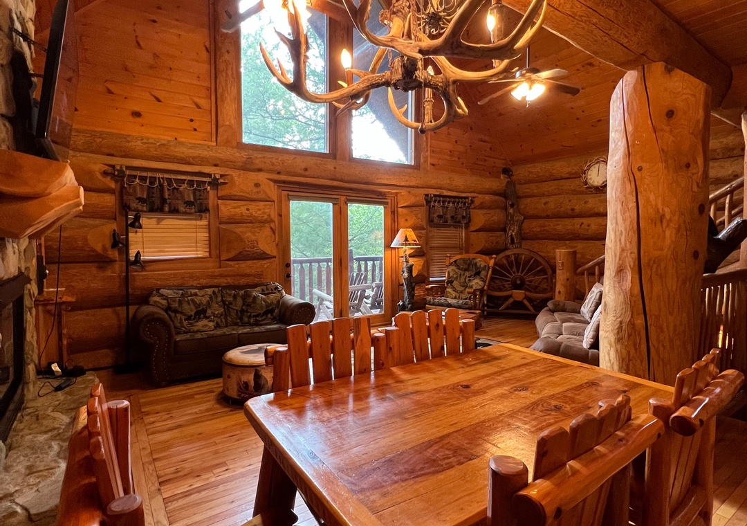 Rustic mountain retreat with soaring wood-beamed ceilings and an antler chandelier. The spacious dining area opens to the living room and private balcony, ideal for cozy meals and cherished moments.