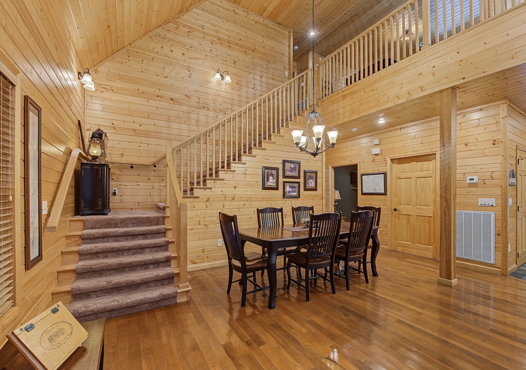 Gather around this inviting dining table beneath soaring pine ceilings, where warm wood tones and rustic charm create the perfect setting for your memorable meals together.