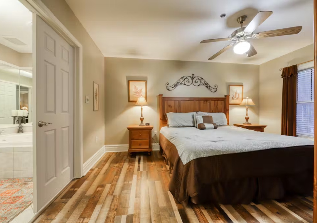 Relax in your charming bedroom with rich wood floors, cozy bedding, and gentle ceiling fan breeze.